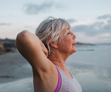Vibrant mature woman enjoying herself on the beach at sunset Ondervoeding